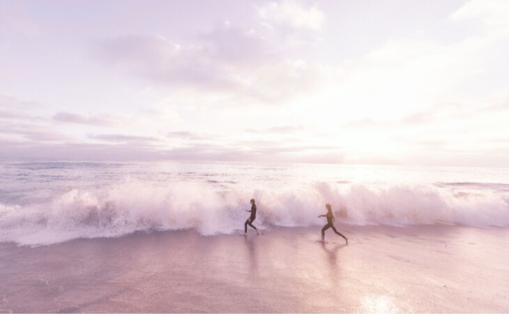 Two people running along a beach at sunrise, symbolising mindfulness, positive change and neuroplasticity benefits.